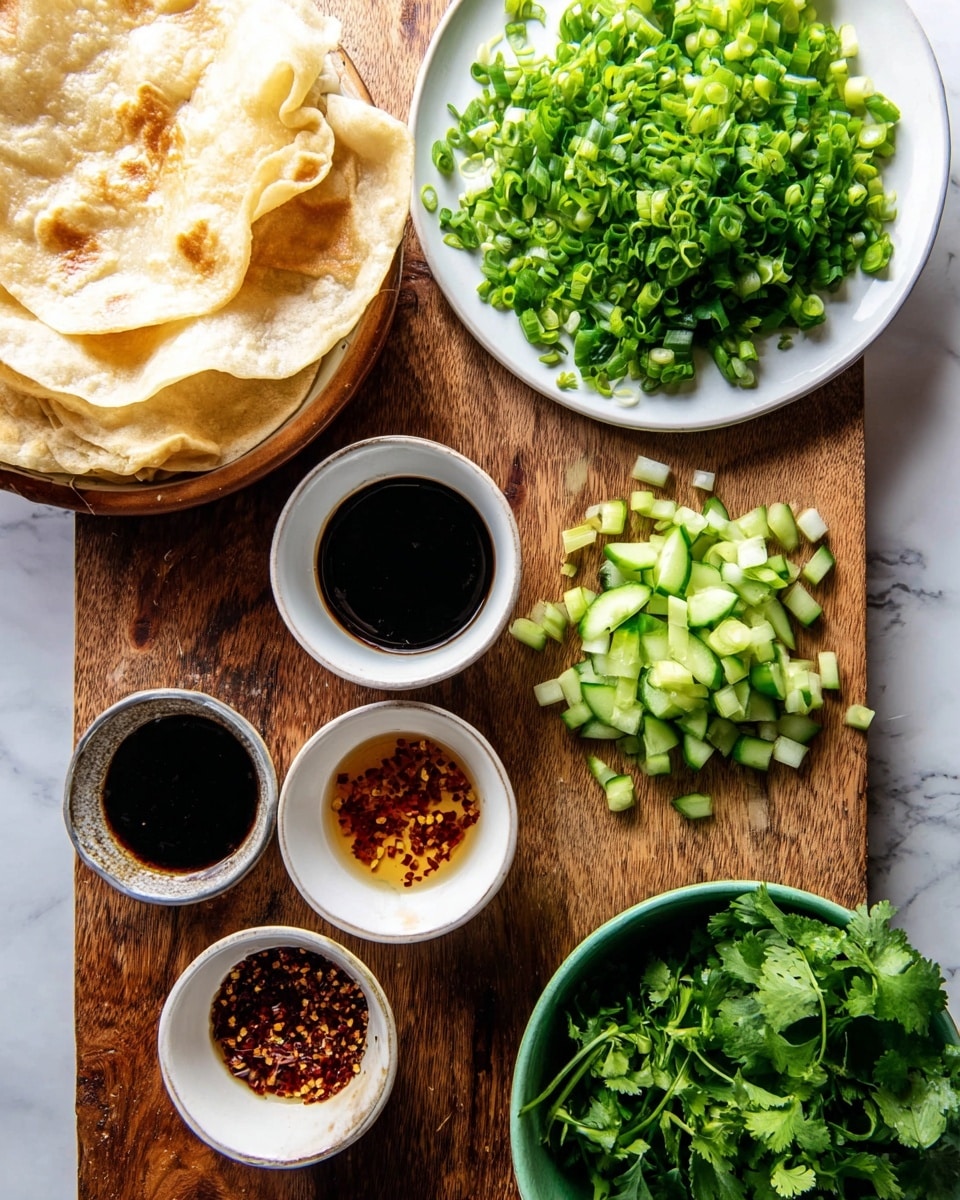 The image shows a top-down view of a wooden board with various ingredients arranged on it. On the left, there is a bowl containing folded light golden flatbreads with a soft texture, placed on a white marbled surface. Above the board, there is a white plate filled with bright green chopped spring onions that have a fresh, crisp look. To the right of the plate, small green cucumber pieces are spread directly on the board. Below the cucumbers, there are three small white bowls: one holds a dark soy sauce, another has a chili oil with red chili flakes, and the third contains a light brown sesame seed sauce. At the bottom right corner, there is a green bowl filled with fresh chopped cilantro leaves. Photo taken with an iphone --ar 4:5 --v 7