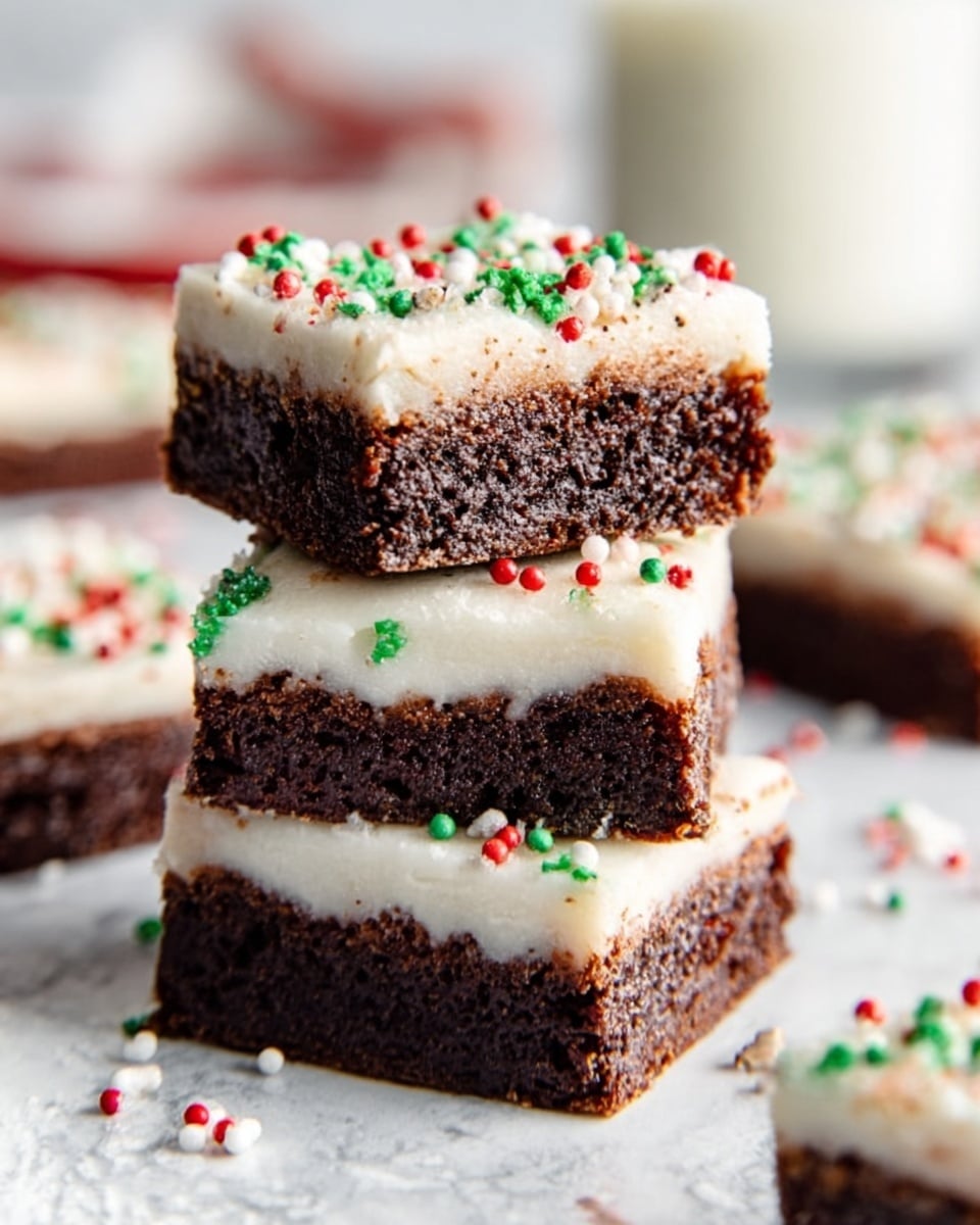 A stack of five square gingerbread dessert bars is shown on a white plate. Each bar has two layers: a thick, soft-looking brown gingerbread base with a textured, slightly crumbly surface, and a smooth, thick white icing layer on top. The icing is decorated with small red, green, and white round sprinkles, and tiny gingerbread man shaped candies are placed on top of some bars. The plate is set on a white marbled surface with a red plaid fabric as the background. One bar is lying flat on the plate showing the side layers clearly, while the others are stacked unevenly on top. Photo taken with an iphone --ar 4:5 --v 7