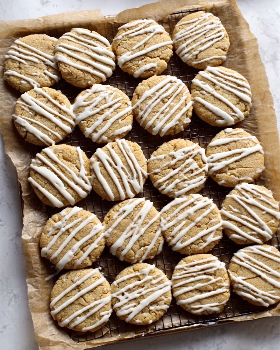 A white marbled surface holds a tray lined with brown parchment paper filled with 24 round cookies, arranged neatly in rows of six by four. Each cookie has a golden brown color and a slightly rough texture, with white icing drizzled in diagonal lines evenly spaced across the top. The cookies look soft but firm, with a thin crust that holds the drizzle well, creating a uniform pattern over the entire batch. photo taken with an iphone --ar 4:5 --v 7