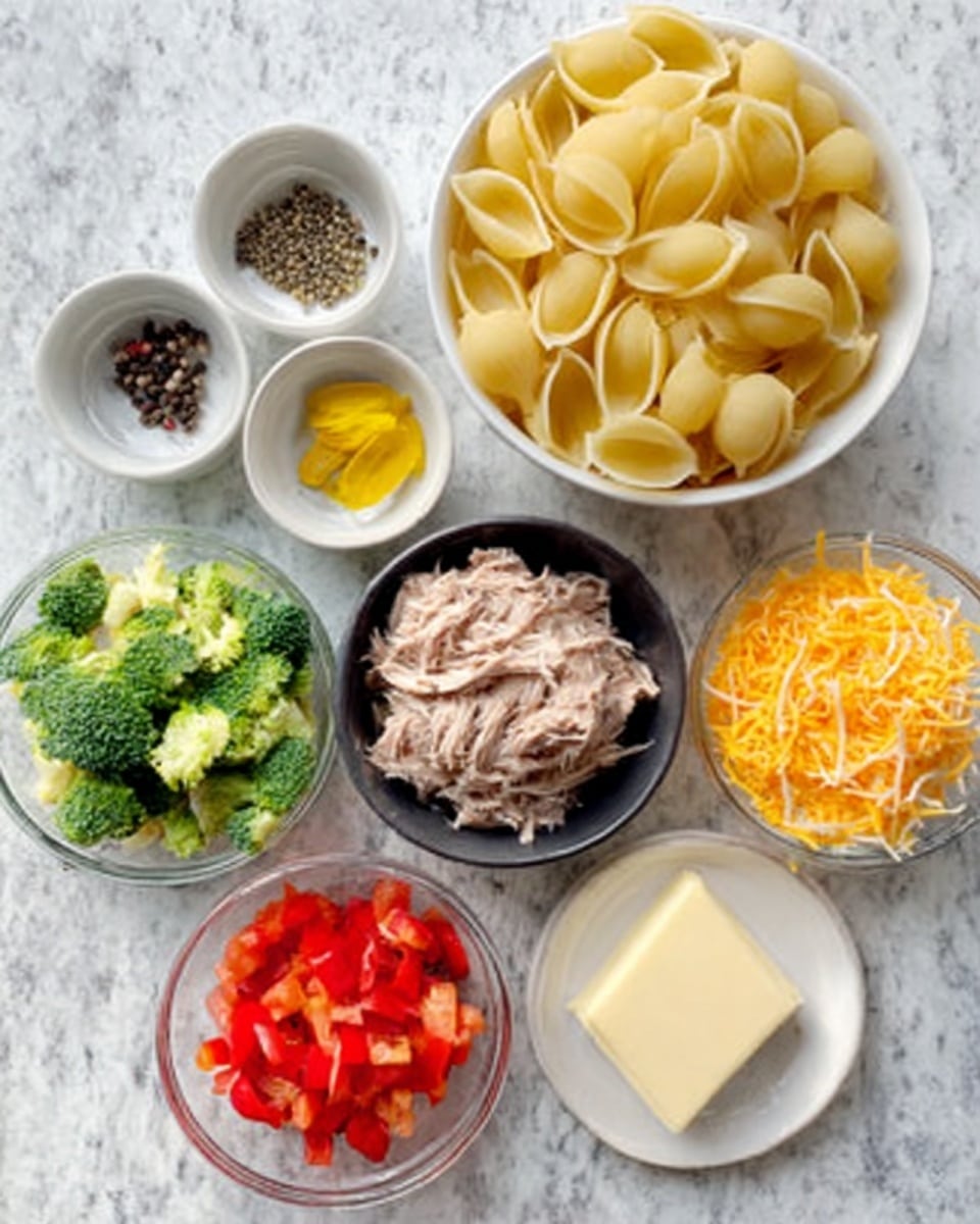 A collection of ingredients arranged on a white marbled surface includes a clear white bowl filled with yellow shell pasta at the top; next to it are small white bowls holding black peppercorns and yellow mustard. A black bowl in the center contains shredded cooked tuna. Around it, there is a white bowl with chopped bright green broccoli and diced red bell pepper, another clear bowl with shredded orange cheddar cheese, and a white plate with a block of cream cheese. All items are laid out neatly, ready for preparation. photo taken with an iphone --ar 4:5 --v 7