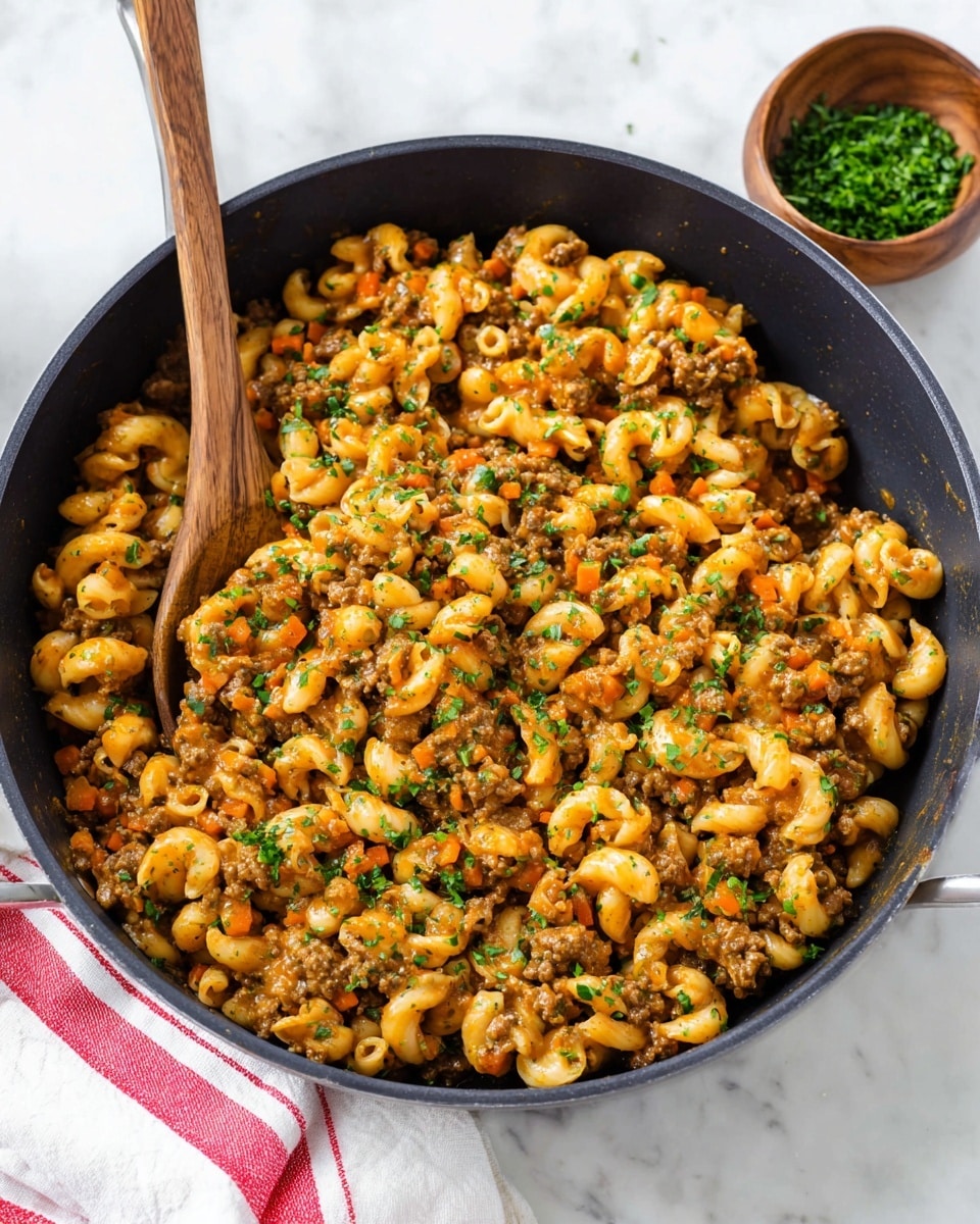 The image shows a pan full of cooked macaroni pasta mixed with a thick, creamy sauce and ground meat. The pasta is yellow-orange from the sauce, and small pieces of cooked carrots add spots of bright orange throughout the dish. The meat is brown and crumbly, mixed evenly with the pasta and sauce. Small green herb pieces are sprinkled on top, giving a fresh look. A wooden spoon is partially buried in the food, ready to serve. The pan is round and white, placed on a white marbled surface. photo taken with an iphone --ar 4:5 --v 7