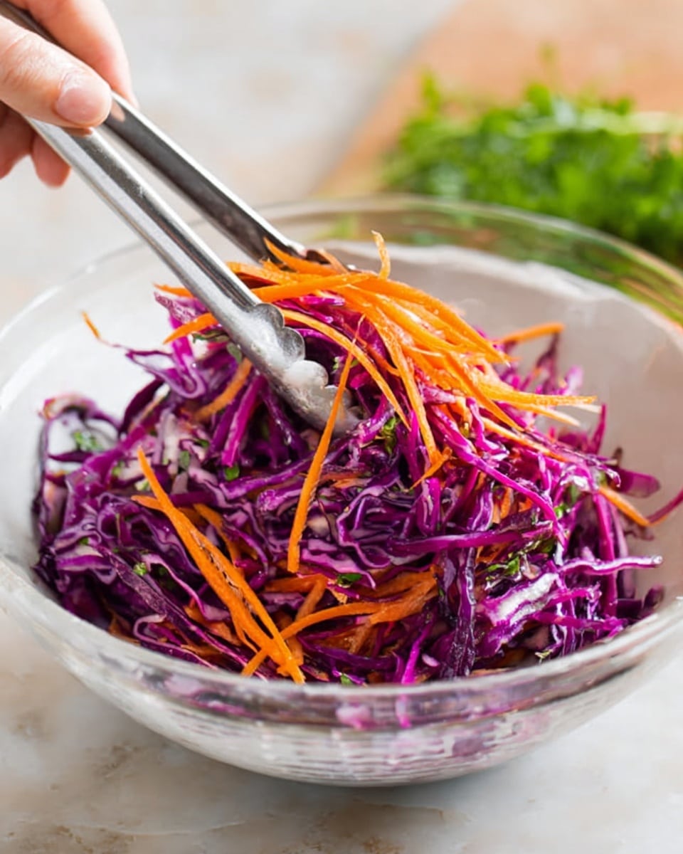 A white clear bowl filled with shredded purple cabbage and thin slices of bright orange carrot on top. The vegetables look fresh and raw, with a crunchy texture. A woman's hand holding silver tongs is lifting some of the vegetables from the bowl. The bowl is placed on a white marbled surface with blurred green herbs in the back. The image looks bright and fresh, showing simple and colorful salad ingredients. photo taken with an iphone --ar 4:5 --v 7