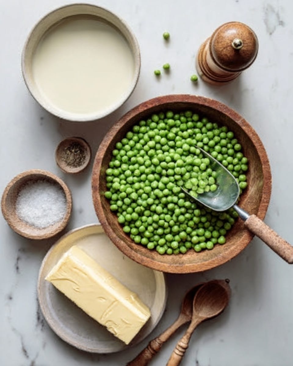 A wooden bowl filled with bright green peas sits on a white marbled surface, with a metal scoop resting on the peas. Nearby, a white bowl holds a creamy white liquid, and a small white bowl contains a pale yellow block of butter with a wooden butter knife. A small bowl of coarse salt and two small wooden spoons lie beside the bowls, along with a pepper grinder. The scene is softly lit, showing the fresh and natural textures of the ingredients. photo taken with an iphone --ar 4:5 --v 7