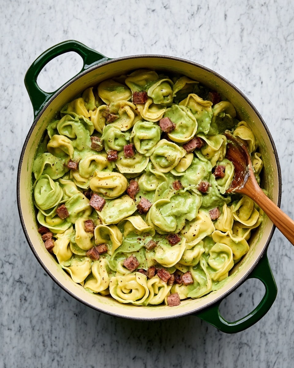 A large white pot filled with three layers of tortellini pasta in two colors: pale yellow and light green, all coated in a smooth green sauce. Small cubes of browned meat sprinkled evenly across the pasta add texture and color contrast. A wooden spoon rests inside the pot on the right, slightly lifting some pasta pieces. The pot has dark green handles on both sides, and the whole scene sits on a white marbled surface. photo taken with an iphone --ar 4:5 --v 7