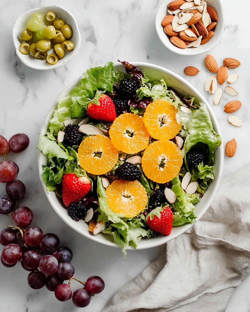 A white bowl filled with fresh salad has a base layer of green leafy lettuce. On top, there are round orange slices, red strawberry slices, black blackberries, and red grapes scattered evenly. Small almond slices are sprinkled over the salad. A woman's hand pours golden-yellow dressing from a small white speckled cup onto the center of the salad. The bowl is placed on a white marbled textured surface with a light grey cloth nearby and a small white bowl of almond slices in the background. Photo taken with an iphone --ar 4:5 --v 7