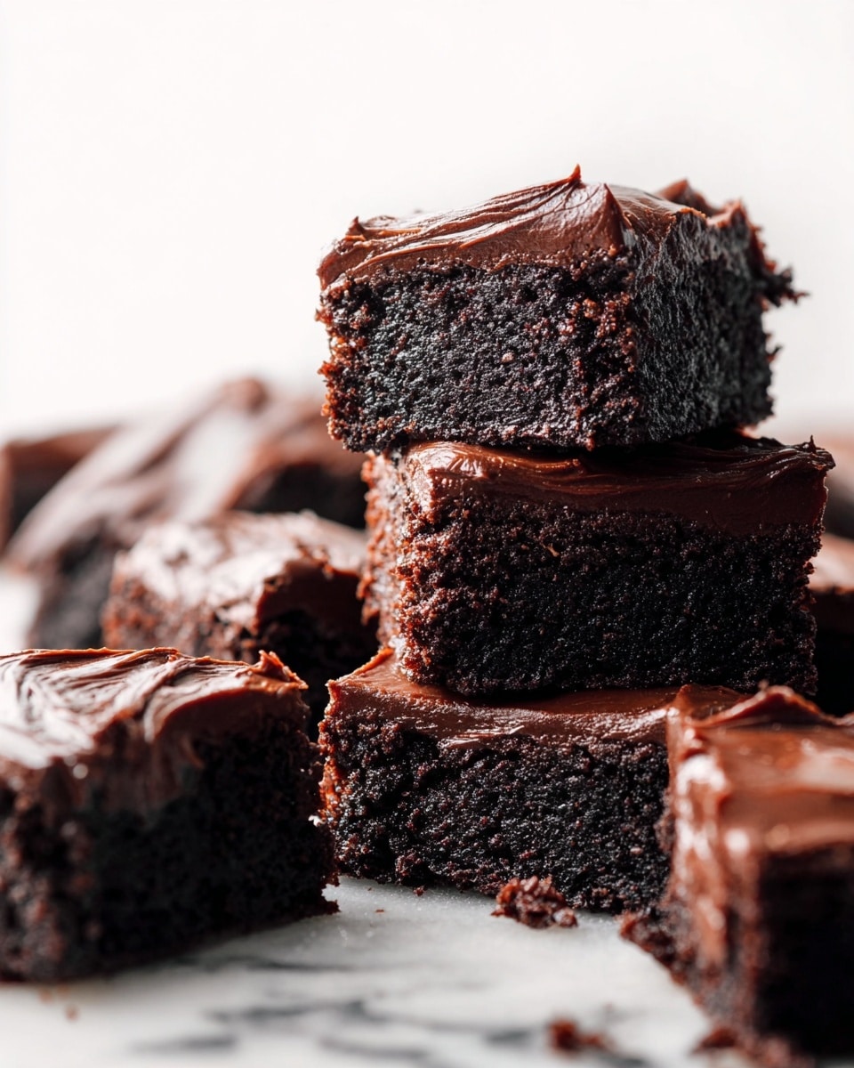 The image shows several rich, dark chocolate brownies stacked and scattered on a white marbled surface. Each brownie has two visible layers: a moist, dense-looking dark brown cake base and a thick, smooth, glossy chocolate frosting layer on top. The brownies appear soft with textured edges and some crumbs around them. The lighting highlights the shiny frosting and the rich, dense texture of the cake. The background is bright and clean, focusing attention on the brownies. Photo taken with an iphone --ar 4:5 --v 7